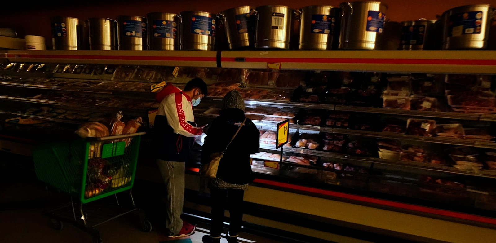 טקסנים משתמשים בפנס של הטלפון הסלולרי כדי לראות את המצרכים בחנות בדאלאס בזמן הפסקת החשמל / צילום: Associated Press, LM Otero