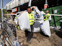 עובד זק"א סוחב שקיות מלאות כובעים לאחר האירוע בהר מירון / צילום: Reuters, מירון