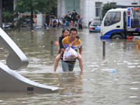 גבר נושא אישה בעיר הסינית ג'נגג'ואו לאחר שגשם חזק גרם להצפות באזור בשבוע שעבר / צילום: Reuters, CHINA DAILY