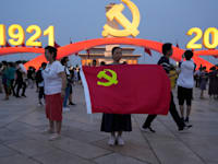 אישה מחזיקה בדל המפלגה הסינית בעת חגיגות מאה שנים להיווסדות המפלגה / צילום: Associated Press, Ng Han Guan