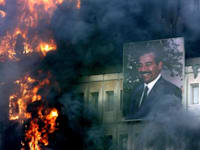 דיוקן של סאדם חוסיין על מבנה עולה באש, בזמן הפלישה של ארה''ב לבגדד / צילום: Associated Press, JEROME DELAY