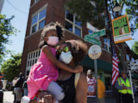 אמא עומדת עם בתה ברחוב גרינווד לציון 100 שנה לטבח בטולסה, אירוע שגרם לפערי ענק בין החברה הלבנה לבין החברה השחורה בארה"ב / צילום: Associated Press