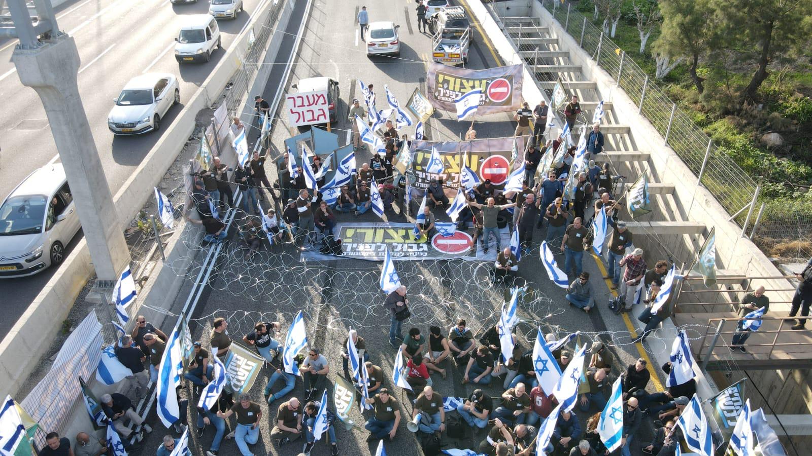 המפגינים שיושבים על הכביש פרסו גדר תיל, אוחזים בשלטים וקוראים ''ישראל לא תהיה דיקטטורה'' / צילום: צילום רחפן: דב גזית