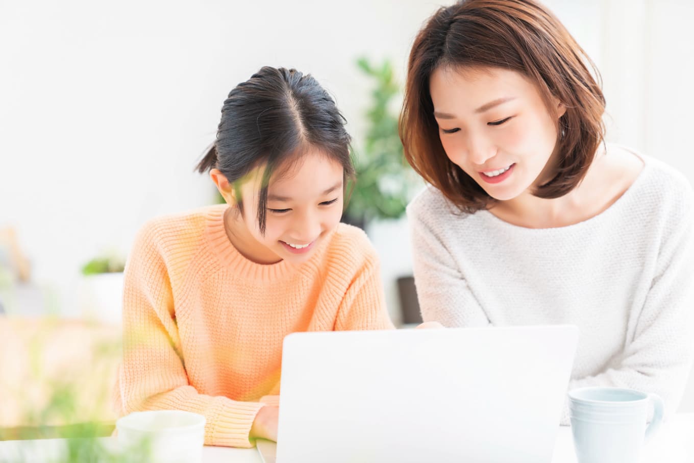 自宅でノートPCを見ながら子どもオンライン英会話に取り組む女の子と保護者のイメージ