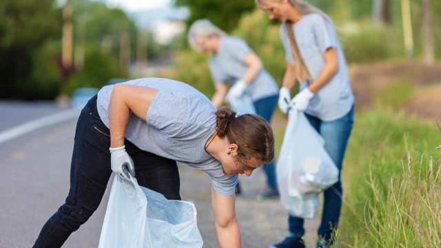 people picking up trash on the side of a road as community service