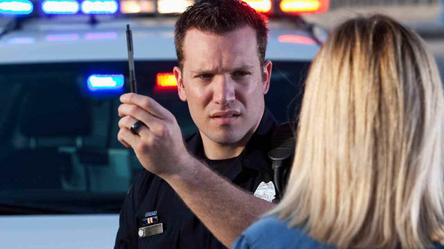 a police officer administering a field sobriety test to a woman