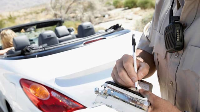 a police officer writing a speeding ticket to a driver