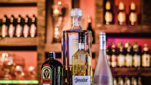 several liquor bottles on a bar, with the background out of focus.