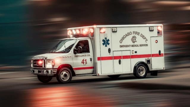 An ambulance speeding down a street with its emergency lights flashing