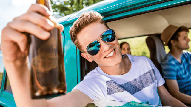 Photo of an underage boy drinking beer in a car.