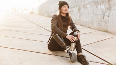 a woman with a prosthesis sitting and looking at the horizon