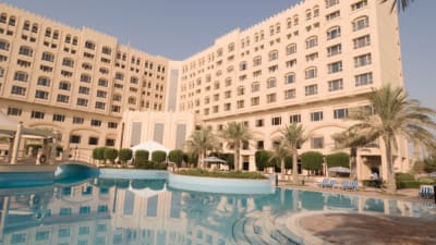 a large hotel with a swimming pool in front