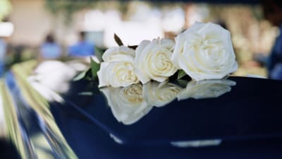 a black coffin with white flowers on top