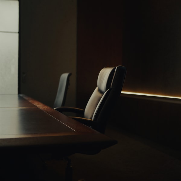 Empty chairs at a conference table, an illustrative image rather than a photograph of our offices