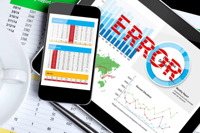 A tablet and smartphone display financial reports, graphs, and the word "ERROR" in red. Papers with numbers and calculations are in the foreground, with a white cup in the top left.