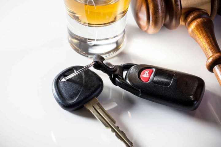 a white table with a gavel, car keys, and alcohol on it