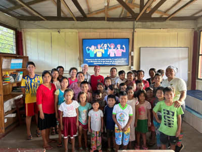 Students and teachers of a partner school gathered in their classroom in front of a screen about inclusion