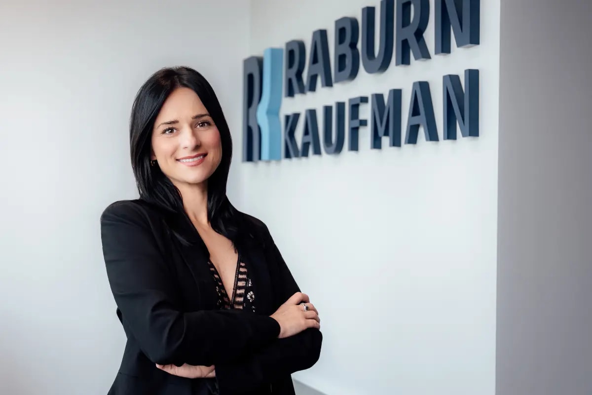 Andrae’ Melancon, Litigation Manager at Raburn Kaufman, standing in front of the firm’s sign