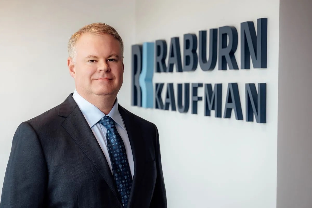 Jonathan Raburn, Managing Partner at Raburn Kaufman, standing in front of the firm’s sign