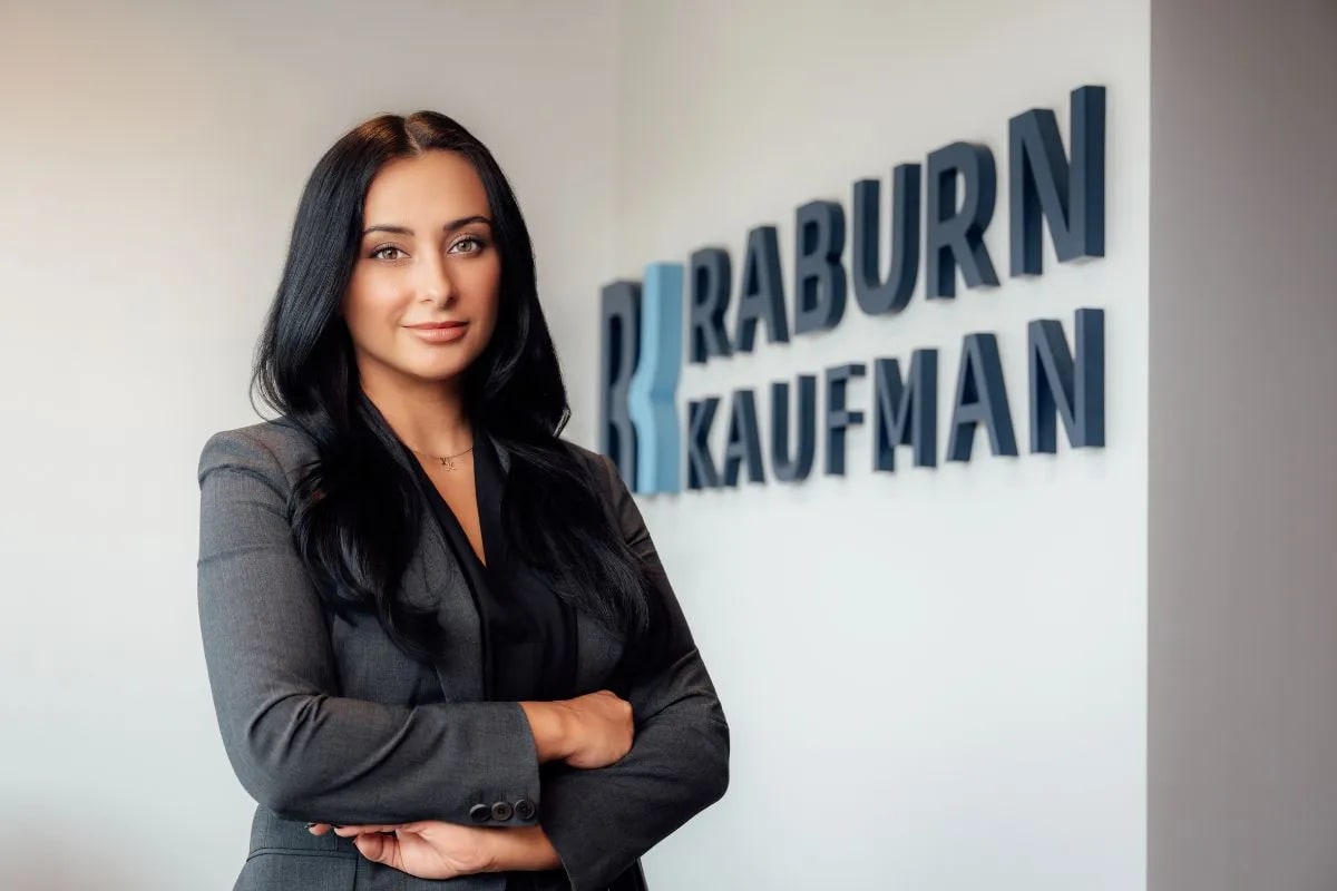 Kyle Kaufman, Partner at Raburn Kaufman, standing in front of the firm’s sign