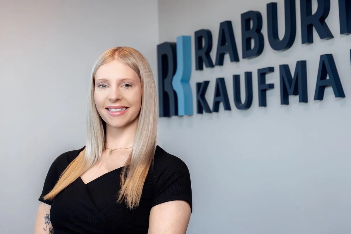 Savannah Cooper, Pre-Litigation Manager at Raburn Kaufman, standing in front of the firm’s sign