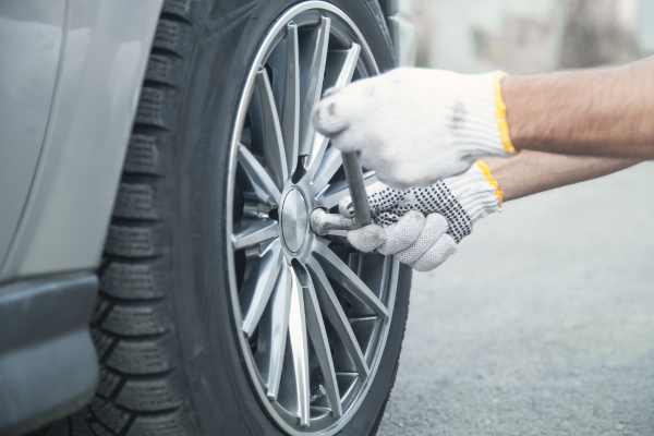 a man putting a wheel with new tires on a car