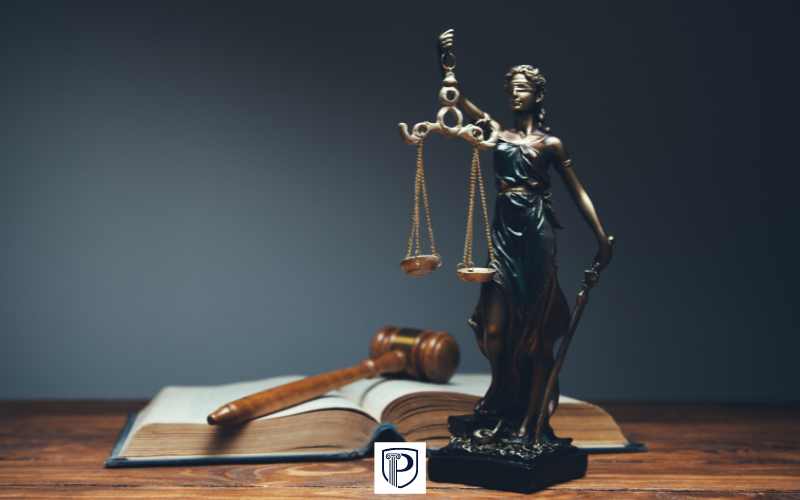 a law book, gavel, and statue of justice on a desk