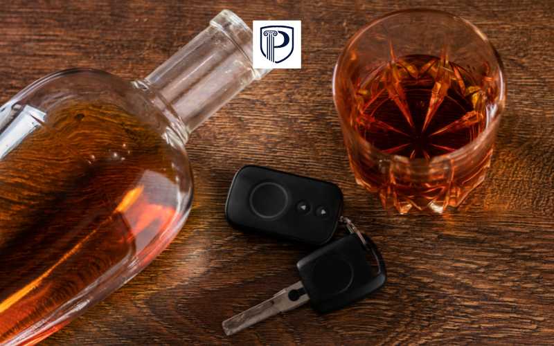 a bottle of alcohol, glass, and car keys on a counter
