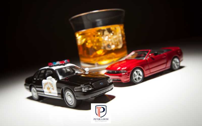 two model cars and a glass of whiskey on a white table