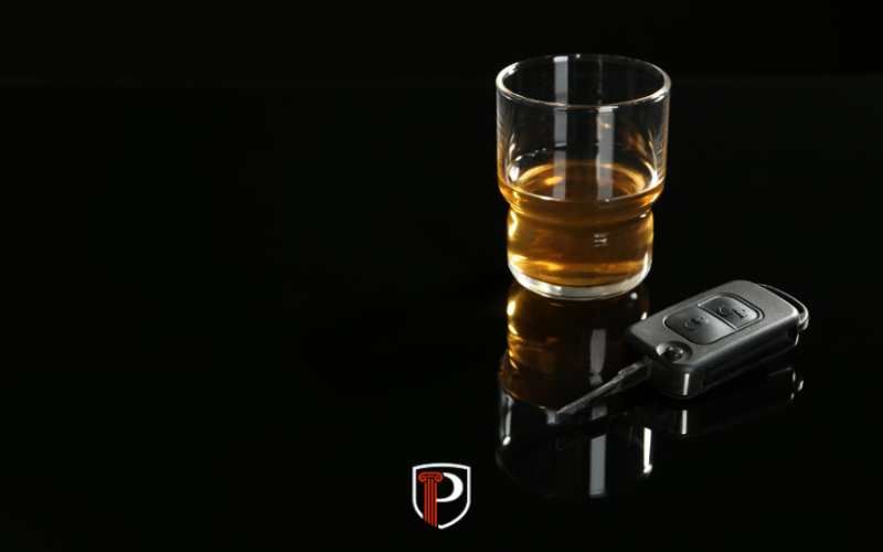 a car key and glass of whiskey on a black background