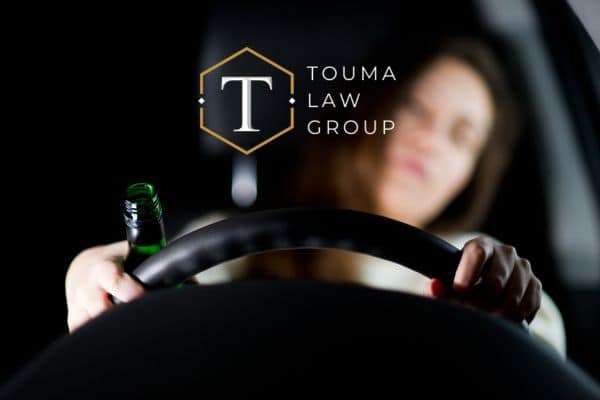 a woman with an open container behind the wheel of her car