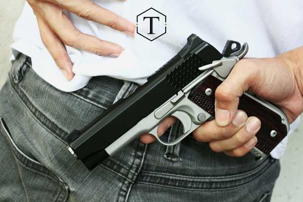 a man putting a handgun in the back of his pants