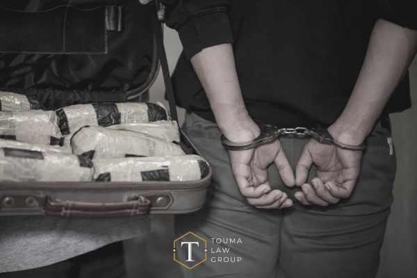 a man in handcuffs next to drugs that he was trafficking