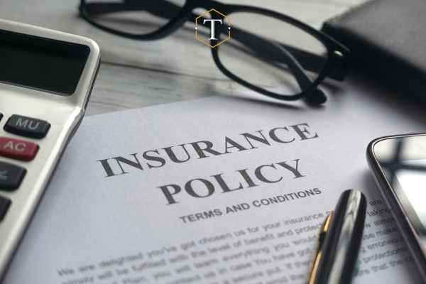 a car insurance form, pen, and glasses on a desk