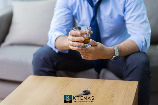 a man drinking in front of a table with his car keys on it