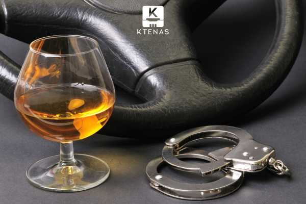 a steering wheel, handcuffs, and glass of alcohol on a table