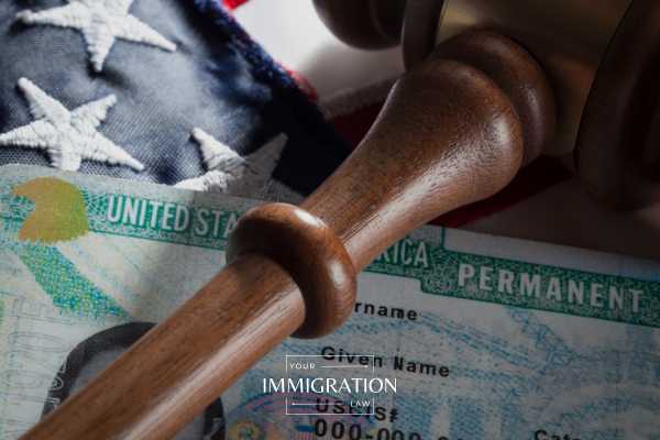a gavel and green card on an american flag