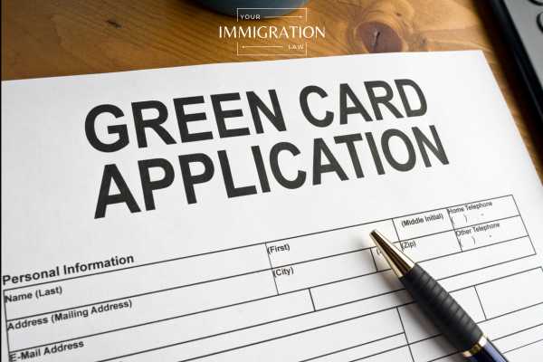 a blank green card application form and pen on a desk