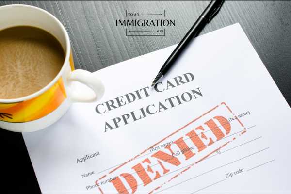 a denied green card application on a desk with a pen and cup of coffee
