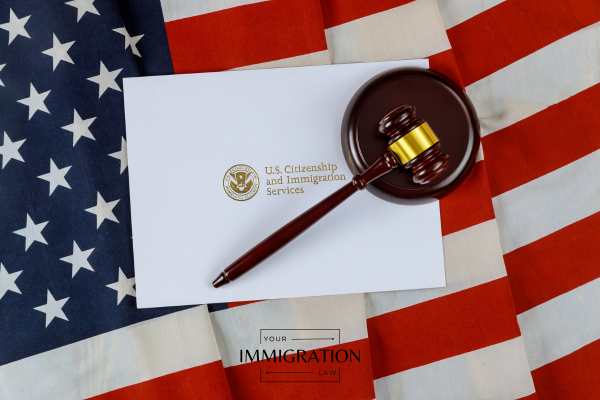 a form from USCIS in an envelope and a gavel on an American flag