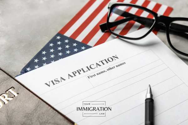 glasses, a visa application, passport, and pen on a table