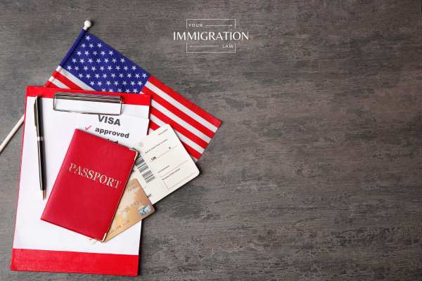 A visa application, passport, US flag, and plane ticket on a black table
