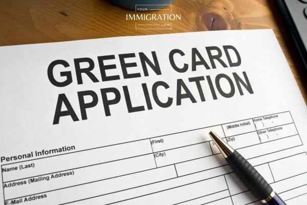 a pen and a green card application on a desk