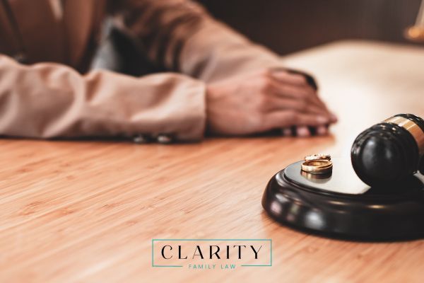 a person sitting at a desk with their wedding rings next to a gavel
