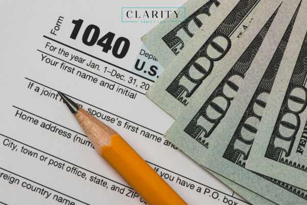 a tax return form, money, and pencil on a desk