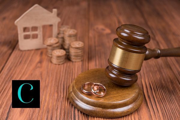 a gavel next to some wedding rings right money and a house behind it