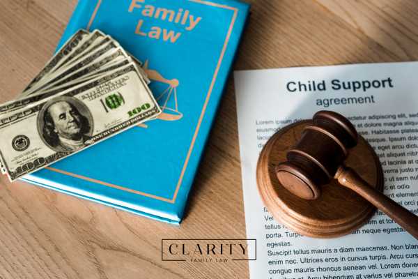 a child support agreement, legal book, money, and a gavel on a desk