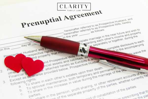 a prenuptial agreement on a desk with a pen and two cut our hearts on it