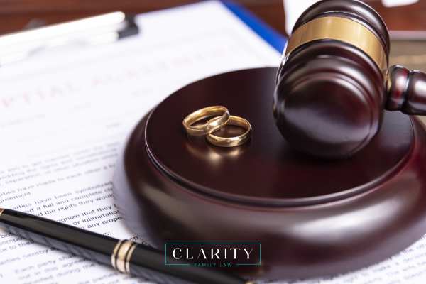 a gavel, wedding rings, and prenup on a desk
