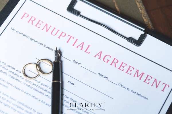 a prenup on a clipboard with a pen and wedding rings
